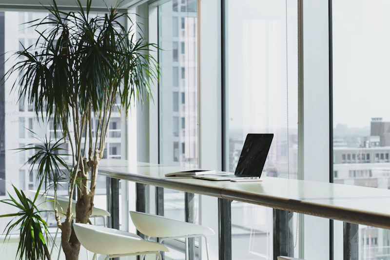 A workstation beside full-height glazing with planting and a city outlook